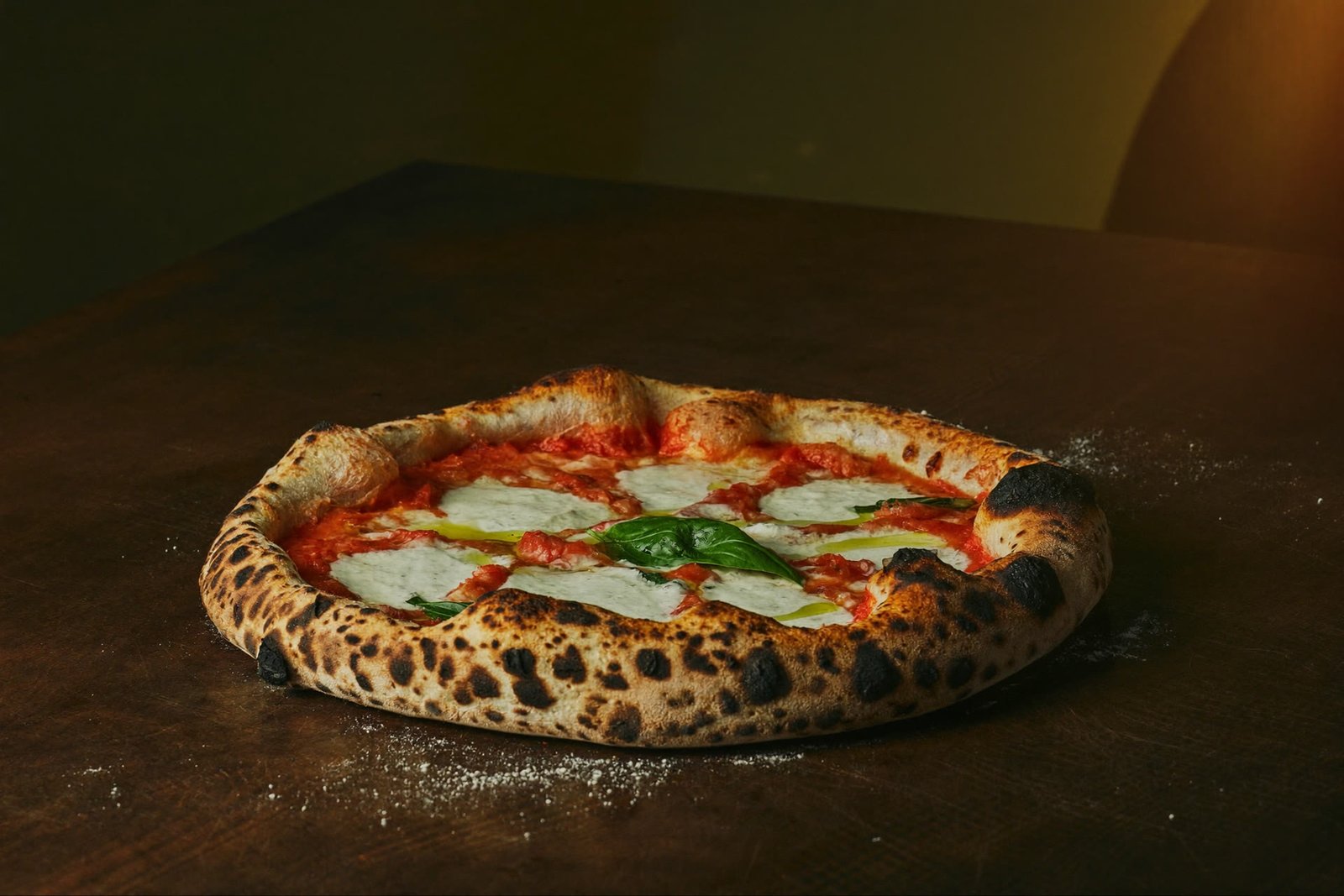 Eine Margherita mit hohem, luftigem Rand auf dunklem Holz