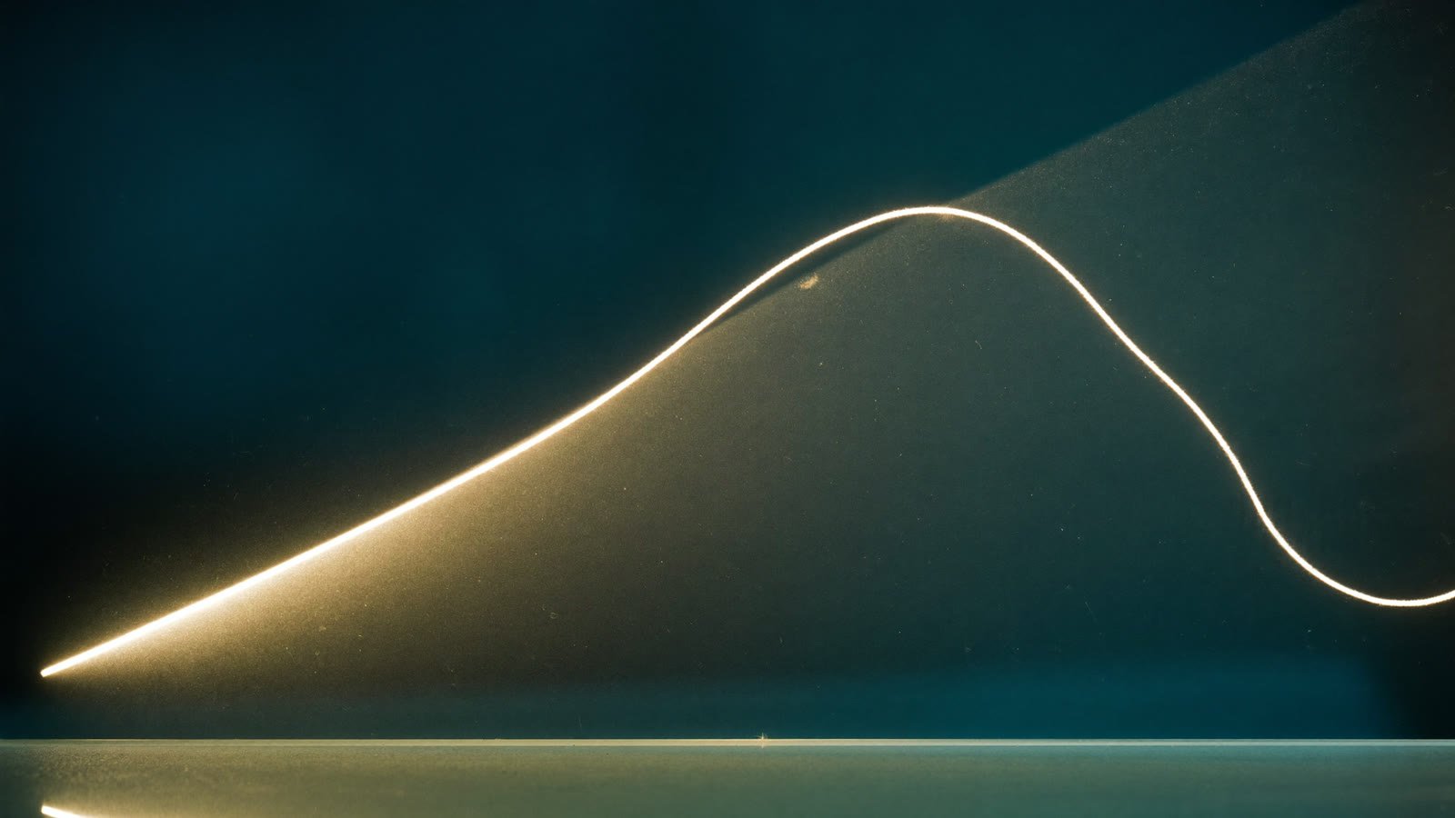 Eine ruhige Kurve aus warmem Licht liegt auf dunklem Glas